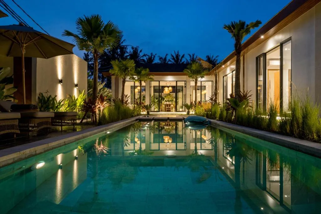 Villa Bahagia swimming pool at night with warm lights and tropical planting